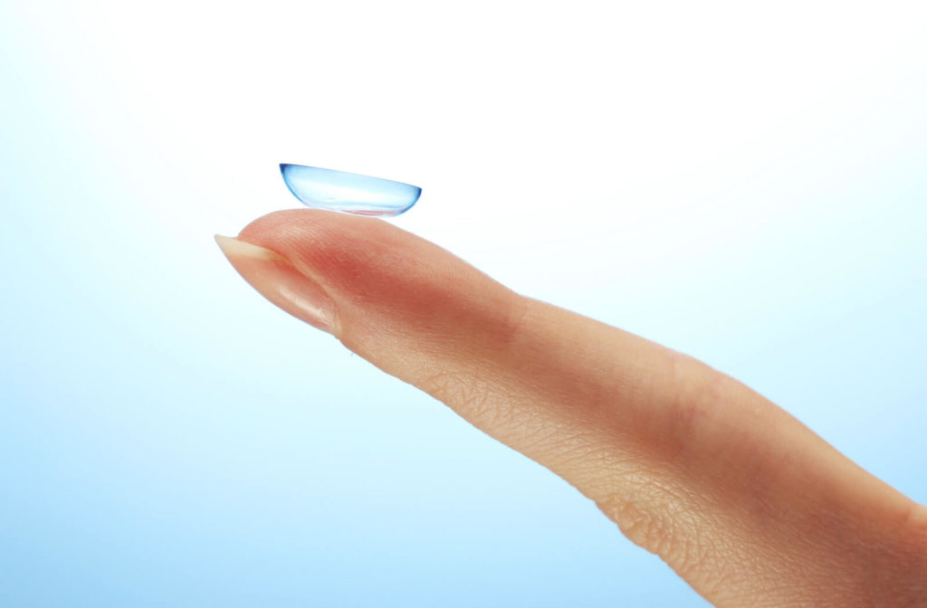 A left index finger of a woman with a contact lens on the tip.