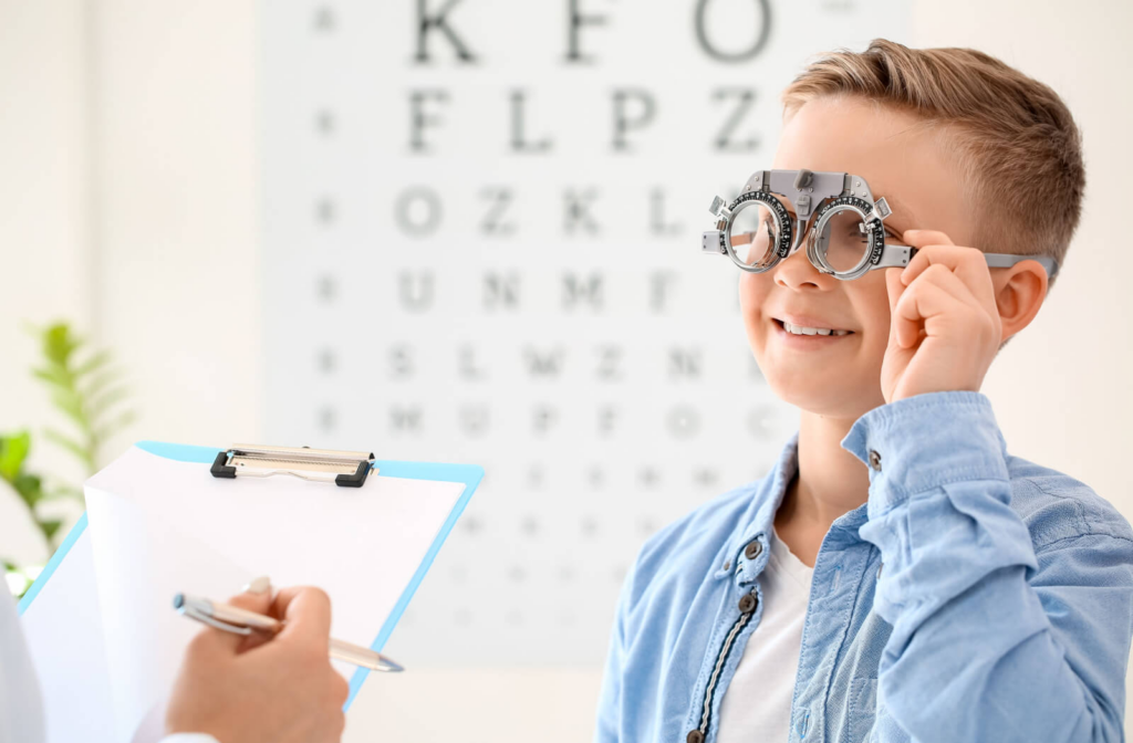 A young boy undergoing an eye exam while the optometrist is checking her clipboard.
