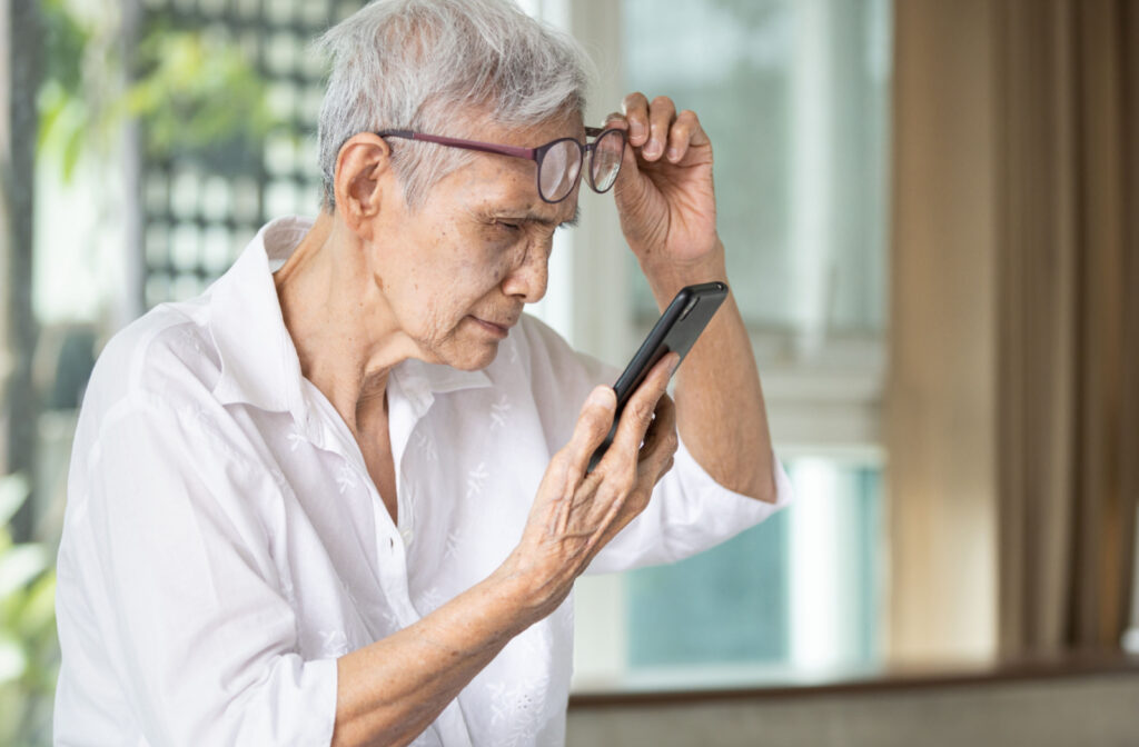 A senior person with myopia leaning closer to her phone to see its content better.