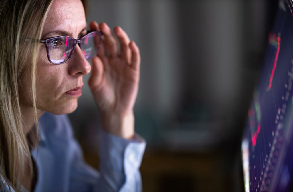 A close up of a woman wearing glasses as she looks at her computer screen.