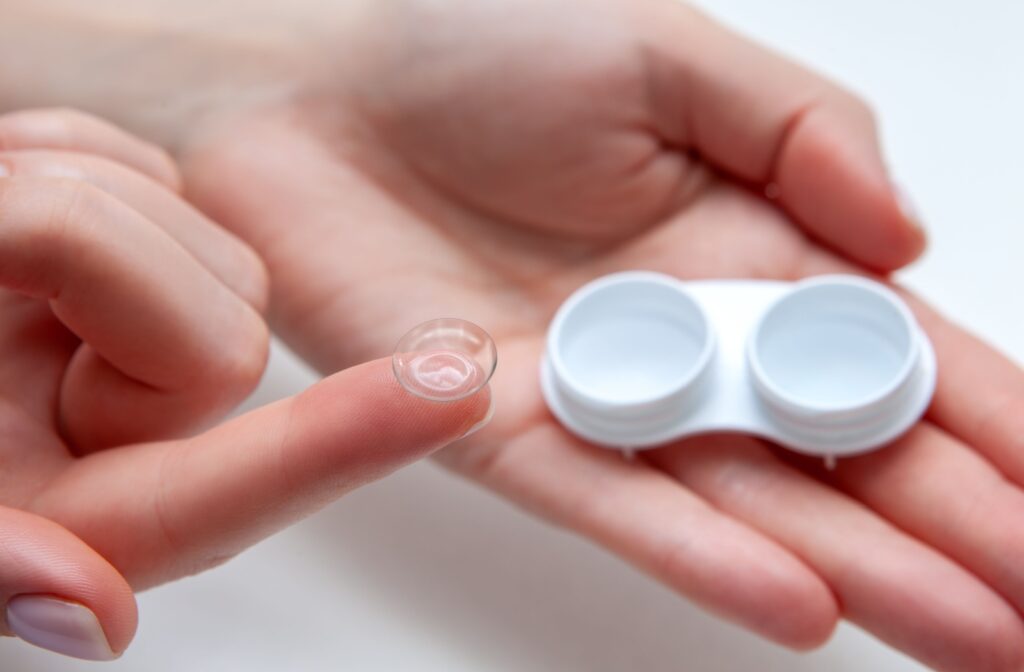 A patient holding a contact lens on her right index finger and a contact lens case in the palm of her left hand.