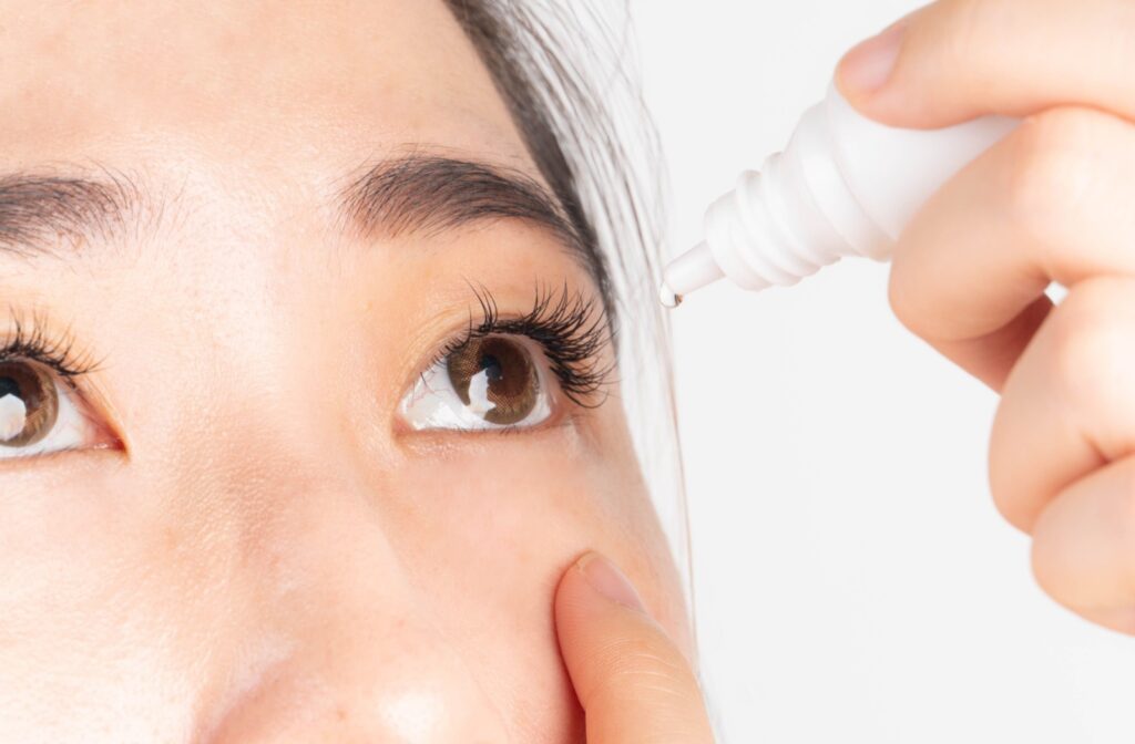 a woman in using eye drops to aid with her uncomfortable dry eye symptoms that are persistent.