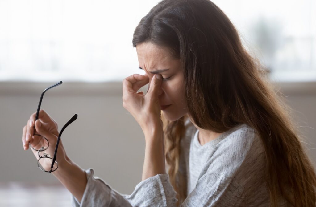 A person taking off their glasses and rubbing their eyes in frustration, wishing for relief from their dry eye.