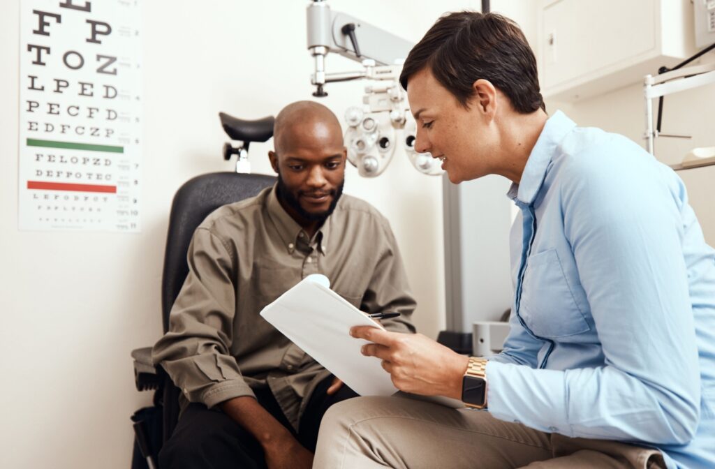 An optometrist goes over their eye exam result chart with their patient.