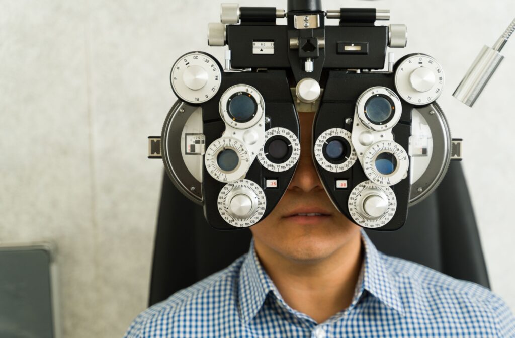 A patient sits behind a phoropter machine for a refraction test during their annual eye exam.